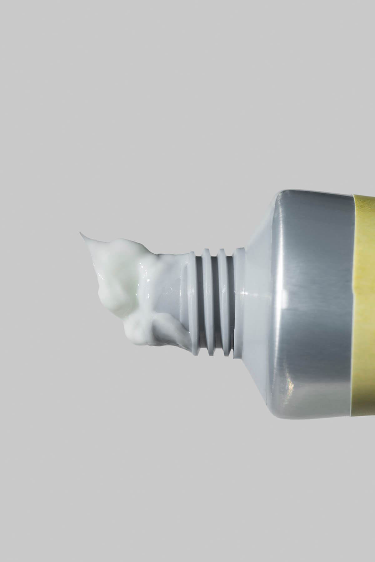 Зубная паста выдавливается из носика тюбика с пастой. Крупный план.